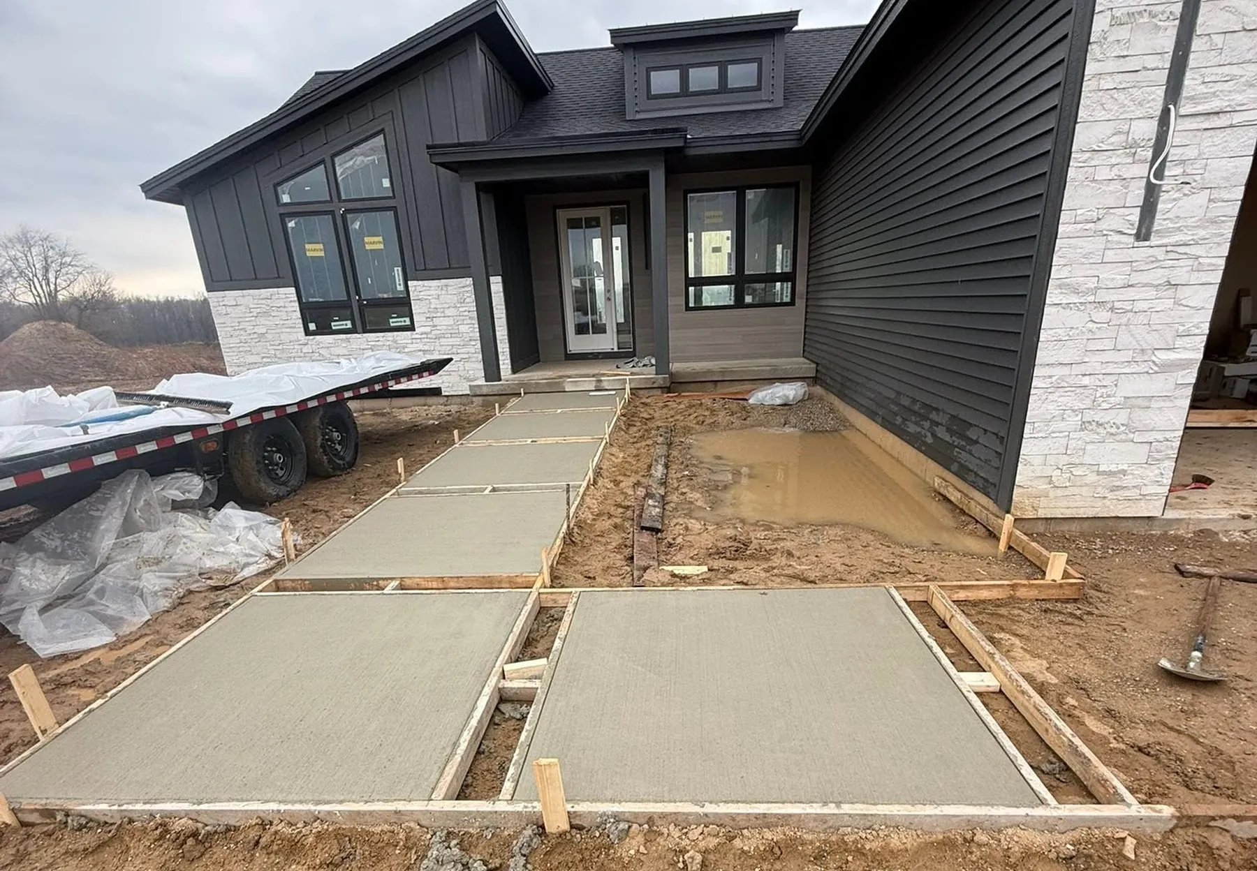 Freshly poured concrete walkway and entry slabs still in the forms at a new build in West Michigan